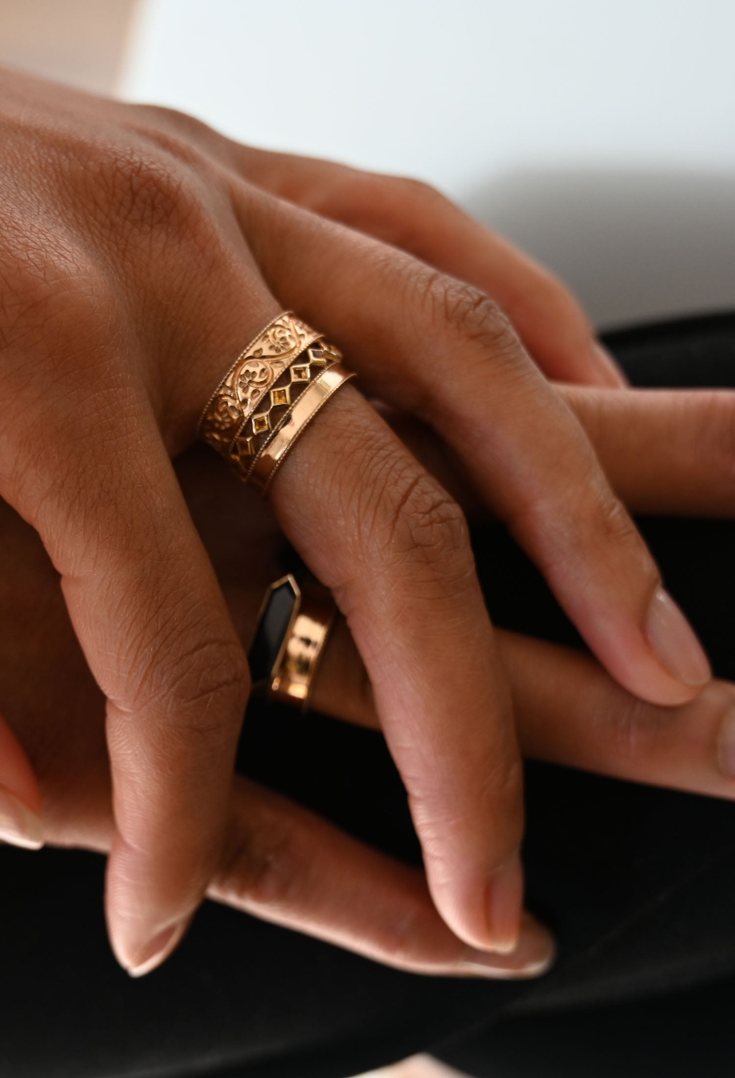Model's hand wearing multiple Metier gold rings in a stack