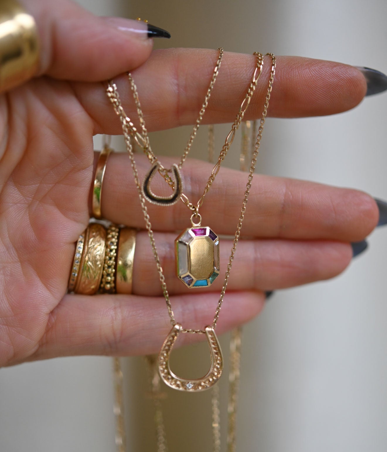 Models hand showing Métier gold necklace and rings