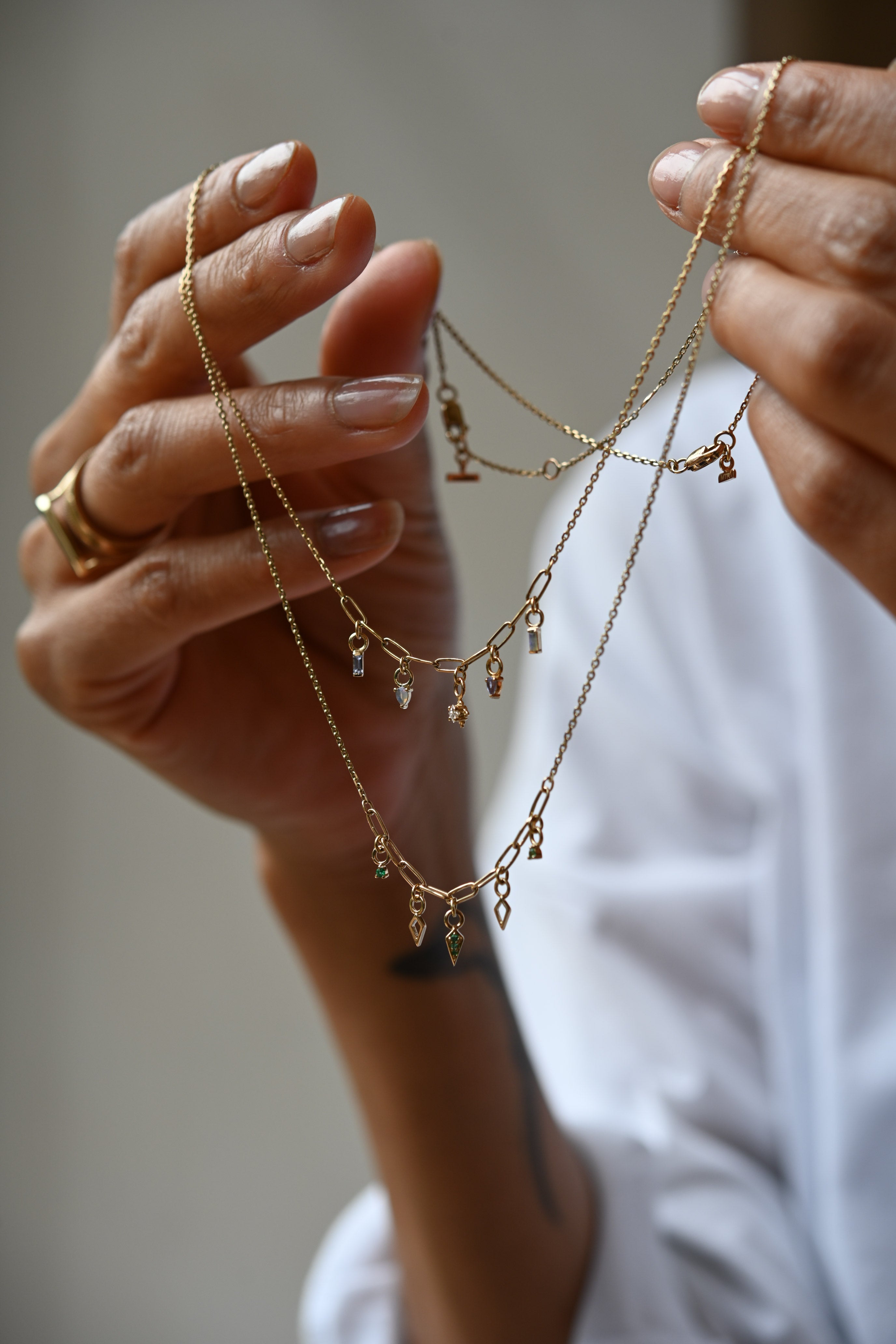 Model holding Metier's gold necklaces from the Create Your Own Collection 