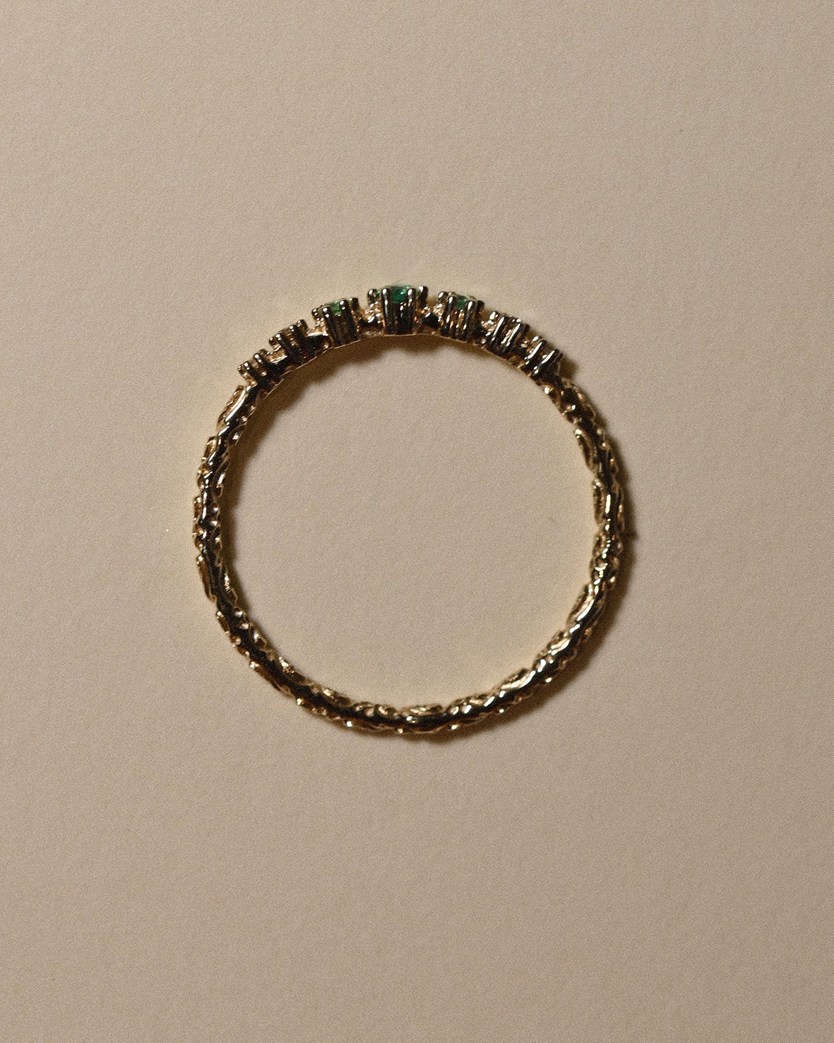 Gold ring with embedded gemstones on a beige background