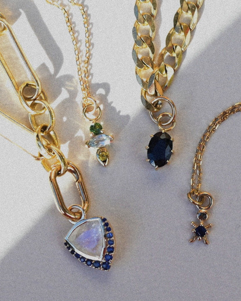 Gold necklaces with various pendants on a light background