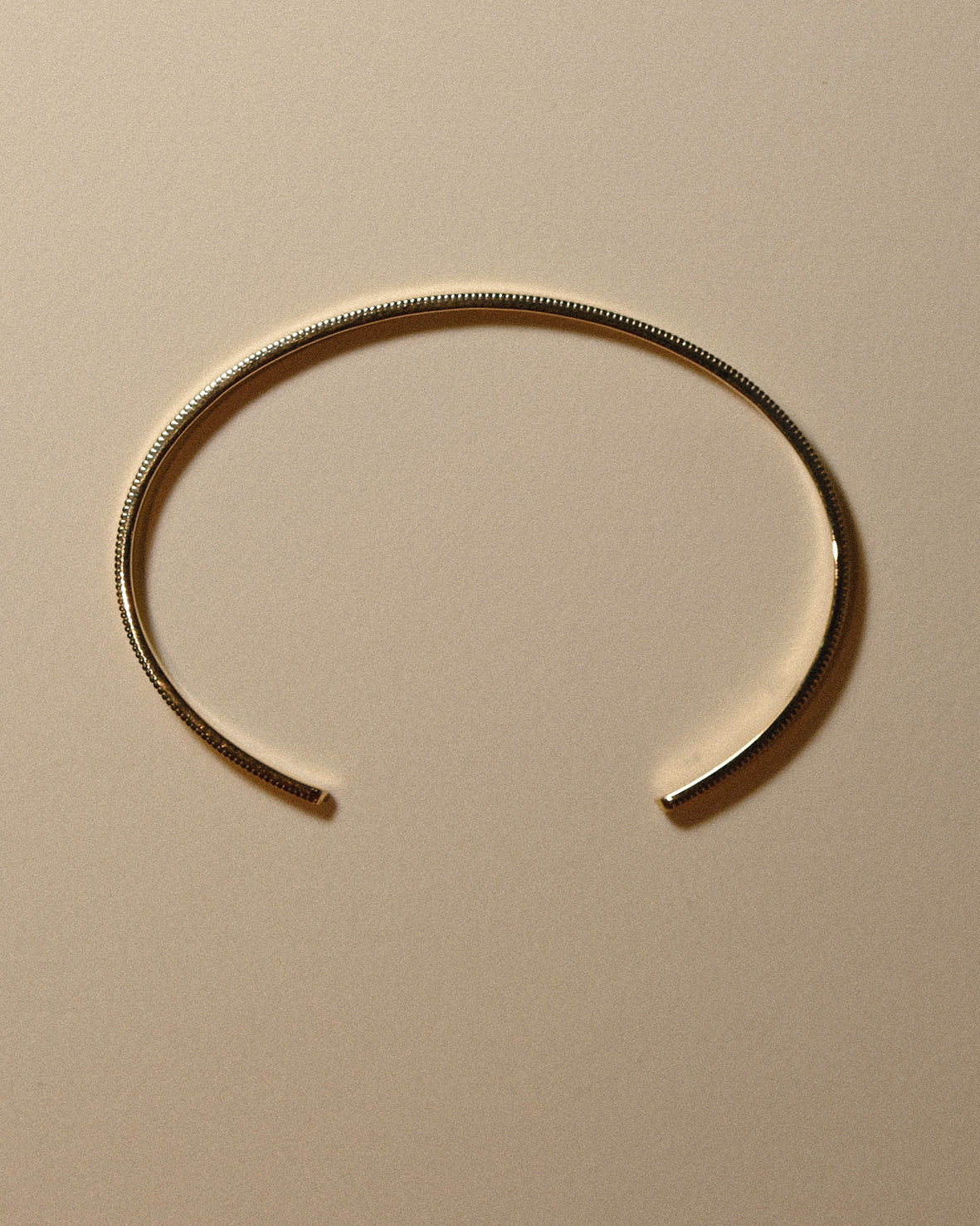 Gold bracelet on a beige background